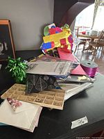 Pile of gift bags, tissue, ribbon spool, curly bow, wood letters tray