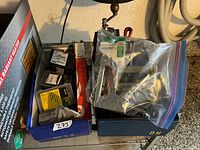 Box containing Arrow staple tacker in clear bag, multiple small boxes of screws/fasteners including DeWalt and John Deere