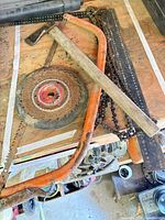 All items on workbench: hatchet, bow saw, circular saw blade, chainsaw chains, ruler