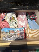 Drawer containing assorted oven mitt, pot holders and towels
