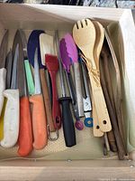 Drawer view with assortment of knives, utensils, bamboo spoons, tongs, spatula, basting brush