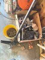 overview of box with steel brackets, spray gun body, pry bar, pail of chain