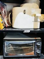Toaster oven on lower shelf, juicer base and accessories on upper shelf