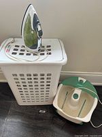 Iron on top of laundry hamper next to foot spa