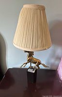 Full view of brass horse lamp on marble base with pleated shade