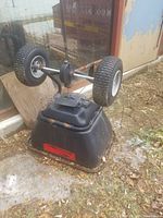 Brinly bagger flipped upside down showing wheels, frame, hopper