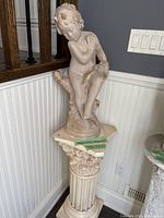 Full view cherub statue on pedestal in corner