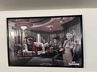 Full view of framed black and white celebrity bar scene print on wall