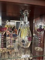 Decanter and three of the glasses displayed in cabinet