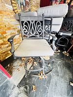 Front view of one cast aluminum bar stool with cushion showing overall style, arms, base and wear