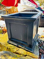 Front and side view of black resin planter showing shape and base
