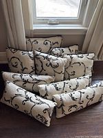Stack of beige pillows with black damask pattern showing rectangular and square shapes