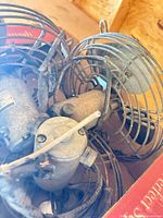 Top view of three metal fans with wire cages inside a cardboard box