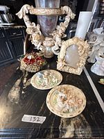 All five items grouped on countertop: cherub urn, photo frame, two plaques, floral basket