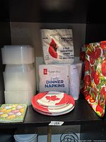 All disposable tableware items grouped on shelf: napkin packages, plates, cups, containers, decorative tray, Easter napkins