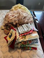 Pile of mixed linens including throw, drapes, tablecloths, towels