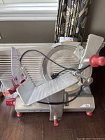 Front view of OMAS slicer showing carriage tray, blade, red controls