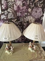 Pair of porcelain cherub table lamps with shades on tabletop