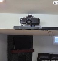 Projector mounted on ceiling bracket above soundbar