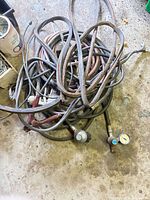 Pile of multiple propane hoses with attached regulators and gauge