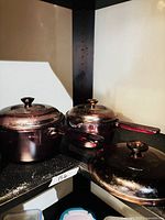 Two purple amethyst glass saucepans with lids and one extra lid