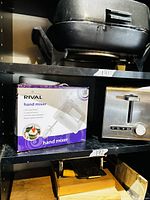 Rival hand mixer box and stainless steel toaster on shelf