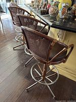 Three rattan and metal bar stools lined at counter