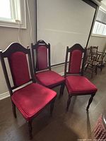 Three matching wood dining chairs with red velvet upholstery displayed side by side