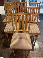 Front view of four chairs showing slat backs and seat upholstery