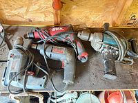 Top view of four corded electric drills with cords and chucks