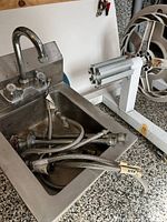 Top view of stainless sink, attached faucet, braided hoses in basin
