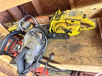All three saws on shelf: Stihl yellow chainsaw, Homelite red chainsaw, Skil circular saw