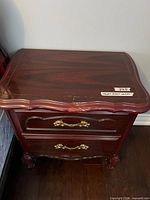 Top view of nightstand showing surface finish, serpentine moulded edge, drawer fronts, brass-tone hardware