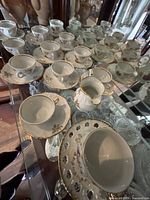 Multiple Winterling teacups and saucers displayed on glass shelf