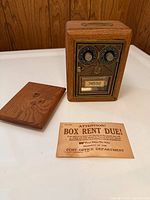 Full view of oak coin bank with back panel removed and postal notice slip