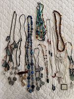 Entire group of fifteen necklaces laid out on quilted surface