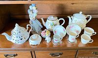 Full lot on shelf showing all teapots, cups, saucers, figurines