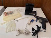 Both glue guns, cradle, nozzle, and glue sticks displayed