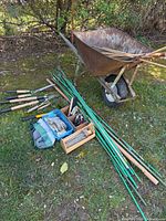 Overview of wheelbarrow loaded with stakes and tools spread on grass
