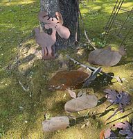 Group of metal yard stakes leaning against tree with moose and leaves visible
