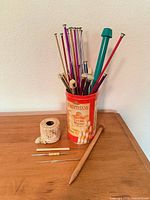 Knitting needles in tin, large wooden needle, cotton thread ball