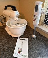 Stand mixer with nested bowls and beaters beside immersion blender and booklet