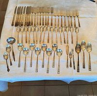 Flatware laid out in rows showing knives, forks, spoons, and additional serving pieces