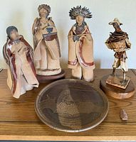 Four figurines, pottery plate on wooden surface