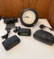 Group shot of all five clocks: wall clock, two LCD alarms, two GE radios