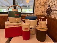 Group of five coolers and jugs on tabletop