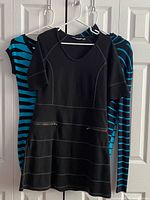 Three dresses hung: black Athleta dress in front with two zippers, two blue/black striped dresses behind
