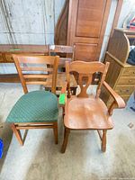 Two chairs: ladder-back with green seat and decorative armchair