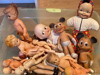 Top view of storage bin showing assorted baby dolls, two Mickey Mouse figures and clown doll