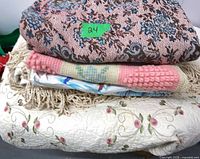 Stacked linens showing tapestry-look top, crochet bedspread, chenille blanket edge, and embroidered coverlet